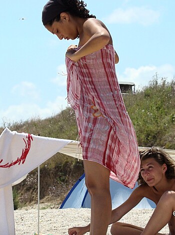 Vulgar description: Two completely naked bitches on the sandy shore with their tits and pussies showing for all to see.