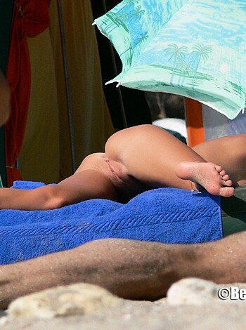 Here's a fucking hot chick, spread out on a goddamn beach towel, flaunting her perfect tits and pussy for the world to see.