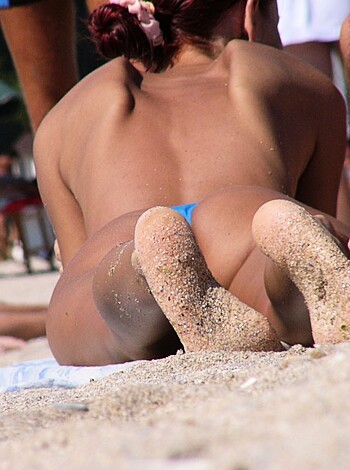 Lying nude on a beach.