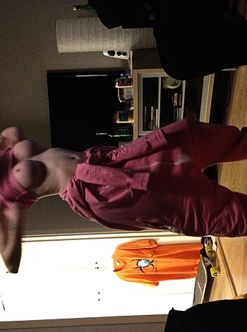 Image depicting an individual with no shirt on, wearing a pink colored piece of clothing while grooving in an erotic manner.