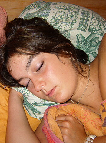 "Here's an image of a fuckin' hot nude chick sleepin' on a goddamn bed with her dumbass eyes shut tight while wearin' a measly little necklace and some bling-ass bracelets."