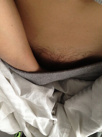 A photo of a man jerking off with his dick out, lying on his tummy and going for it hard without any clothes on.