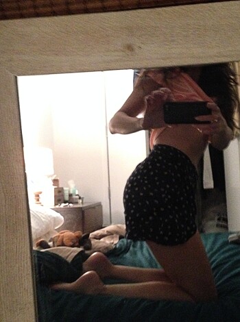 "Yo dude check out this hot chick's ass and leg reflection in the mirror while she sits on some fuckin' bed, gettin' all sexy like."