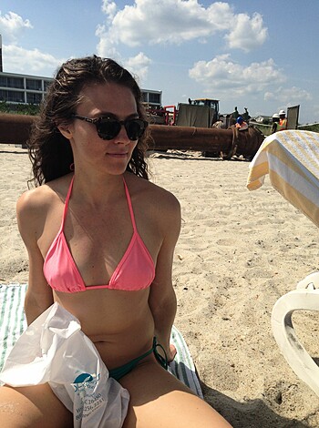 A fucking hot chick in a pink pussy bikini bra, leanin' back in a beach chair, checkin' out the fuckin' waves and grinnin' like she just got ass-fucked while holdin' up a towel.