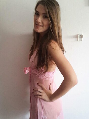 A busty chick in pink lacy underwear standing all sexy-like with one hand on her fuckable ass.