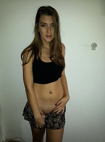 """
Here's a chick with a flat stomach showing off her belly ring. She's wearing a tight-ass shirt, and some panties that barely cover her cunt. You can see her tits from every angle, 'cause the lace is all clingy like that. And she's posin' in front of a wall with a dumb-ass flower pattern on it, just to add to the cheesiness of the whole damn shot.
"""