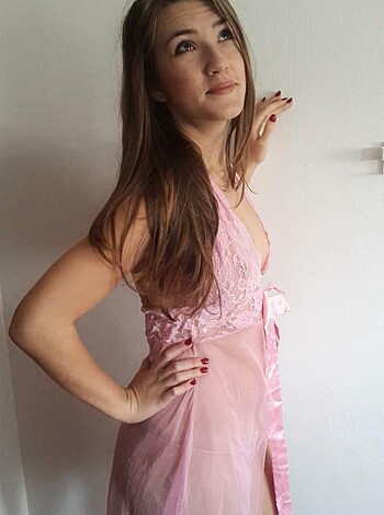 Here's a factual description of the image: In this picture, you can see a slutty bitch with huge tits, dressed in pink lingerie, flaunting her boobs for some fucking dick!