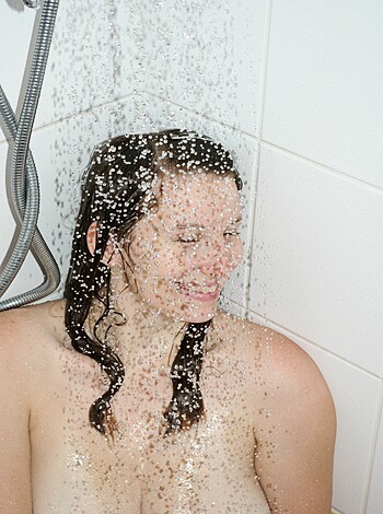 The busty blonde with perky tits takes a fucking shower while a stream of water splashes on her smooth, wet pussy lips.