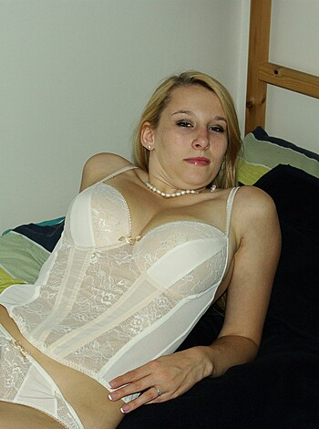 A naked chick lies on her back with a sexy bra on, waiting for the camera to capture her tits.