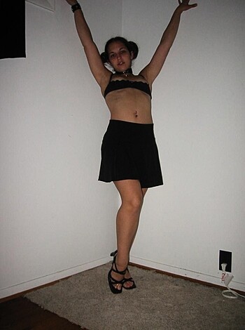 A naked bitch with a hot ass, holding her arms up while she poses on some bricks or shit.