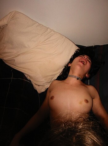 A scantily clad chick lies naked on a bed while some guy goes down on her from behind, rubbing his dick through her blonde hair.