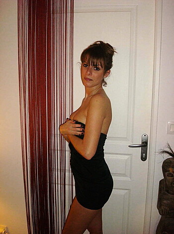 Look at this goddamn picture of some hot-ass slut who's flashing her tits for the fucking camera! She's in a tight black dress that just barely covers her ass cheeks, and her hand is on her chest, almost like she's trying to hide how much of a tit-show she's giving off. Seriously, this is the kind of shit you only see on the internet or in porno movies - total fucking perfection!