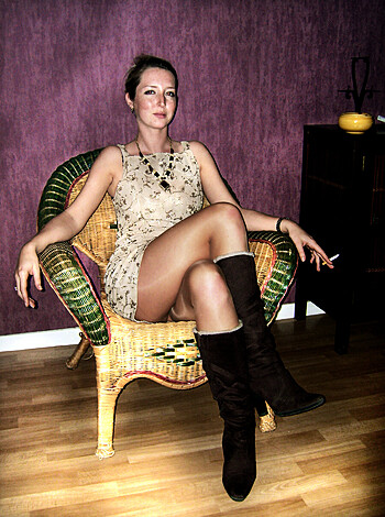 Vulgar description of image: A bitch with her legs crossed and pantyhose-clad ass crack showing, sporting boots and a fucking dress.