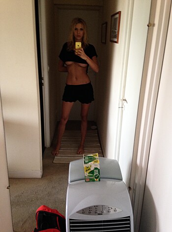 A naked chick flashes her tits in the mirror while taking a shit.