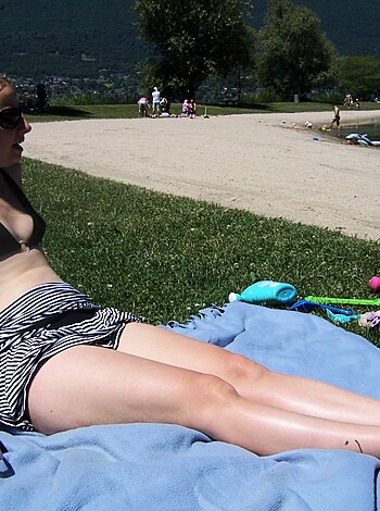 A smokin’ hot blonde babe is getting some rays on the sandy shore, with her tits hanging out and flapping in the breeze.