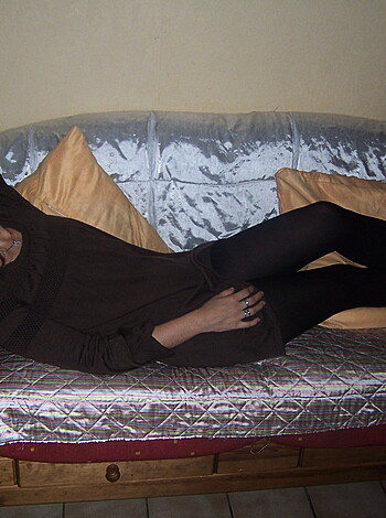 This is an uncensored image of a scantily clad bitch sitting on a cushy sofa, her tits hanging out like two melons, her ass poking through the air like a fuckin' volleyball.
