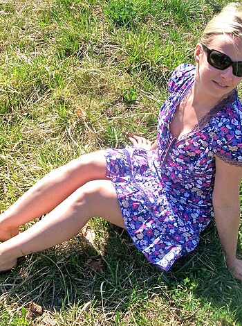 A fuckin' bitch in a flower print dress is stretched out on some green shit, with her head resting on a pillow while her tits are poppin' out like melons.