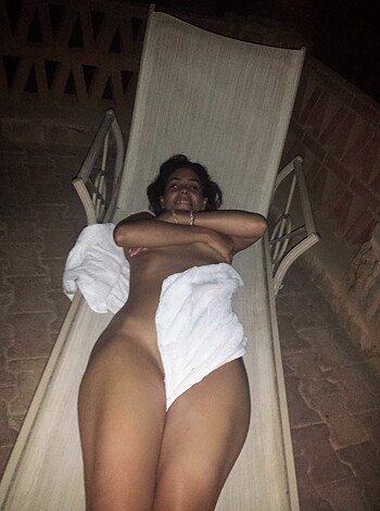 A naked chick lays her ass down on a fuckin' towel while basking on a goddamn beach chair, son!