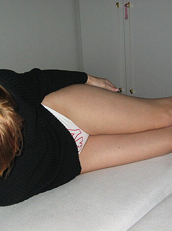 "A bitch laying on the sheets with her naked ass up in the air and some dude's leg in between her spread cheeks."