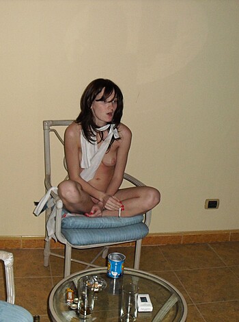 A nude chick with tits and no bra on some chair.