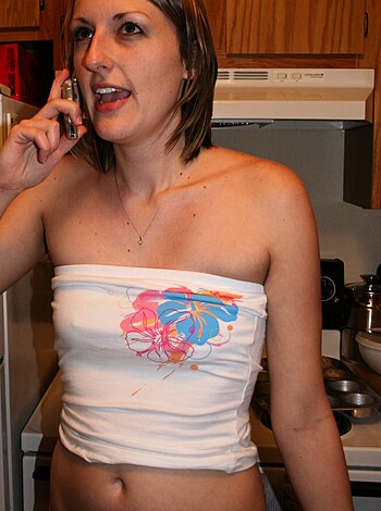 A naked bitch stands in her kitchen, chatting on the fucking phone.