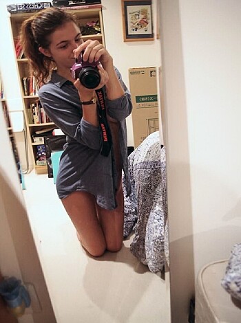 A naked chick taking a mirror selfie while fucking her phone with her cocksucker lips.