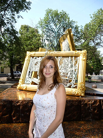 A hot babe strikes a pose next to an enormous, shiny-ass framed piece of art made outta fuckin' glass.