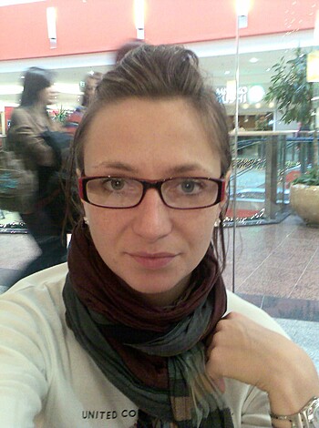 Here's a fuckin' pic of some cunt sittin' down sporting specs n' a fuckin' scarf while that blonde bullshit she got is tied up in a tight ponytail.