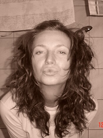 Here's a fucking close-up of some hot chick with curly locks covering her face. She's rockin' a white tee and looks like she's daydreaming or something. There ain't no nudity or explicit shit in this pic, though.