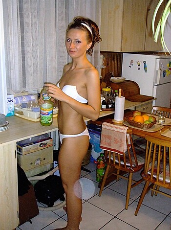Vulgar description: Here's a fucking hot babe in her sexy lingerie holding a goddamn can of soda while she stands bare-chested next to the fridge and countertop in a kitchen, looking all sexy as hell.