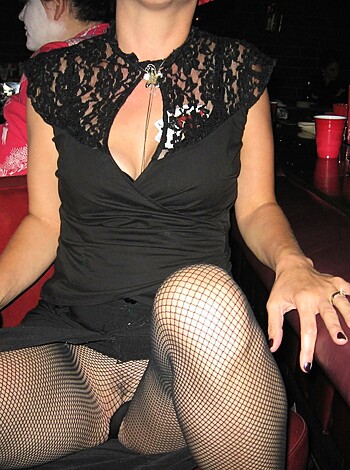 A hot babe in tight fishnets sits on a barstool with her fucking legs crossed, showing off her sexy dress with some slutty cutouts.