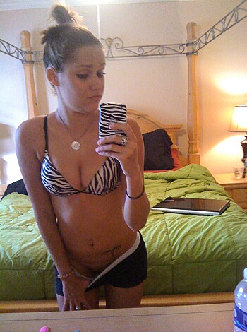 "Check out this hot slut posing nude in her bedroom, with her sexy black bra on display for all to see. She's got a killer body, with those massive titties and curvy ass. And that fucking zebra bikini? Damn girl, you lookin' fine as hell."