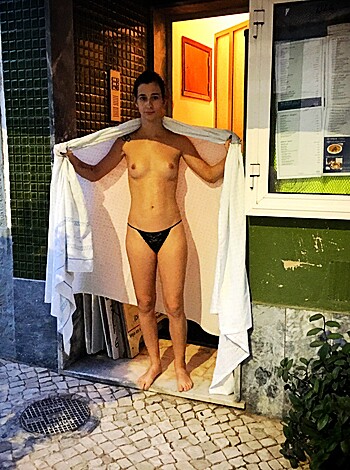 A hot naked chick using a bathroom towel as a skimpy robe, standing by the side of a hotel room door.