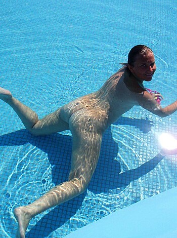 A blonde bombshell's ass floating in a swimming pool, clad in a skimpy bottom.