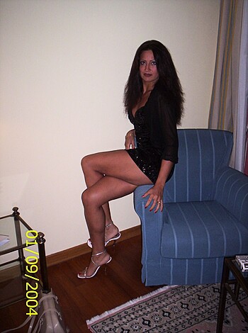 The broad-assed bitch is fucking seated on the leather cushion of that sofa, and she's rockin' some hot little dress that shows off her curvy hips and ample tits like a goddamn work of art.