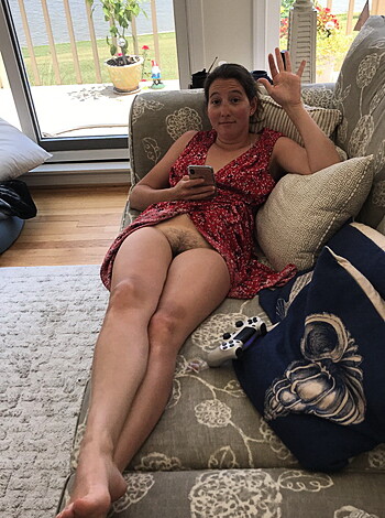A naked, barefoot chick lounges on the sofa, her tits hanging out.