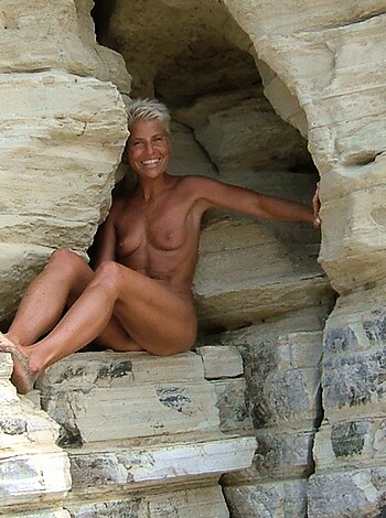 Here's the nude chick perched on a rocky cliff with her pussy hanging out for all to see.