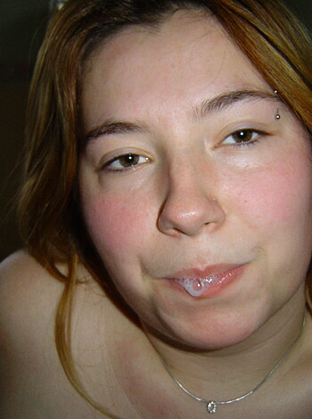 "Here's an image of a busty tatted chick with a tongue ring and nipple bulls, lickin' her lips like she just found a stash of candy."